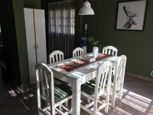 uma mesa de jantar branca com cadeiras brancas em Casa Verde Palmares em Godoy Cruz