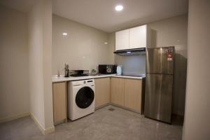 a small kitchen with a washer and a refrigerator at OOAK SUITES AT MONT KIARA KUALA LUMPUR in Kuala Lumpur