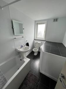 a bathroom with a tub and a sink and a toilet at Homely 3 bed town centre flat in Peterhead