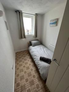 Cama pequeña en habitación pequeña con ventana en Homely 3 bed town centre flat en Peterhead