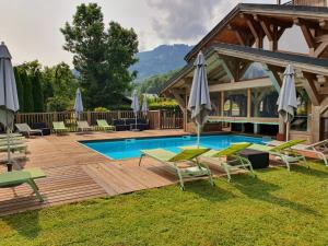 a pool with chairs and umbrellas next to a house at Hotel-Spa Le Morillon Charme & Caractère in Morillon