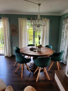 a dining room table with green chairs and a chandelier at Seeliebe mit Sauna und nur 50 mtr. bis zum Strand in Senftenberg