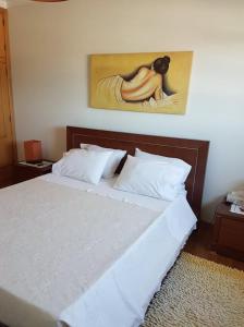 a bedroom with a bed with a painting on the wall at Suite em Viana do Castelo in Viana do Castelo