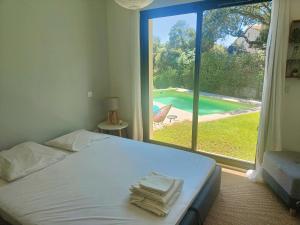 een slaapkamer met een bed en een groot raam bij Villa Echappé à 15 min de la mer in Cournonsec
