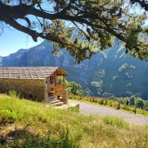 un pequeño edificio en una colina con montañas en el fondo en La Cabaña María, en San Roque de Ríomiera