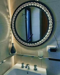 a bathroom sink with a round mirror above it at Aires del Norte Apart in San Miguel de Tucumán