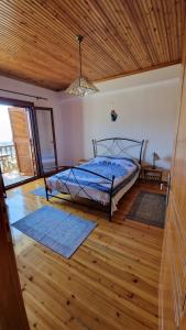 a bedroom with a bed with blue sheets and wooden floors at Crissimo apartment in Panagia