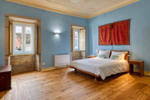 a blue bedroom with a bed and two windows at Casa Trebaruna - refúgio numa aldeia do interior in Proença-a-Velha