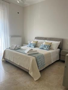 a white bedroom with a large bed with blue pillows at Le Cupole di Palermo in Palermo