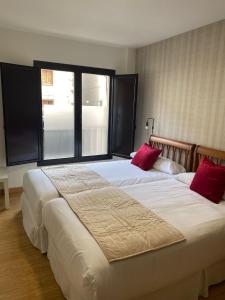 a bedroom with two large beds with red pillows at Apartamentos Palacio Azcárate Calle Calvario in Ezcaray