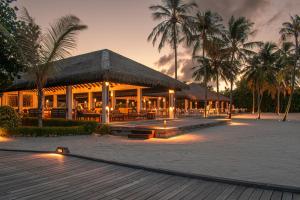 ein Resort mit einem Gebäude mit Palmen und Lichtern in der Unterkunft Noku Maldives in Manadhoo