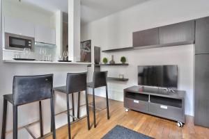 a kitchen with two black chairs and a television at Appartement Quartier Parc Georges Brassens in Paris