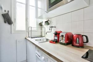 a kitchen with a sink and a red appliance on a counter at Appartement Quartier Parc Georges Brassens in Paris