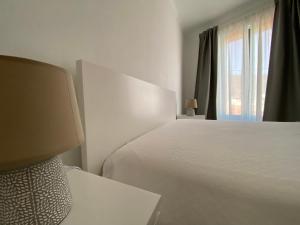 a white bedroom with a bed and a window at Casa da Amoreira in Odeceixe