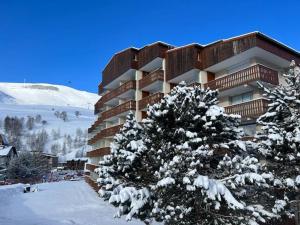 un edificio con un árbol cubierto de nieve delante de él en 4 pers, pied des pistes, WIFI, Netflix, Lave-vaisselle, en Les Deux Alpes