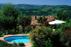 a swimming pool with an umbrella and an umbrella at Casale con vista sui Monti Sibillini e piscina in Amandola