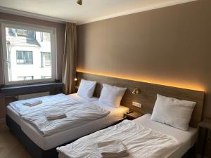 a hotel room with two beds and a window at Hotel Petite Königsallee SELF CHECK-IN in Düsseldorf