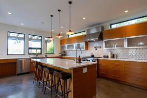 a kitchen with wooden cabinets and a large island with bar stools at Tree Fern Guest House in Tofino