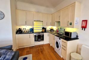 a small kitchen with white cabinets and a microwave at Craigielea Apartment 3 in Lerwick
