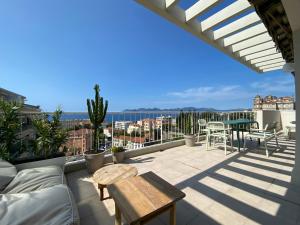 a patio with a couch and tables on a balcony at Vue mer à couper le souffle - nouveau entièrement rénové in Cannes