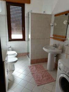 uma casa de banho com um WC, um lavatório e uma máquina de lavar roupa em The Garden em Tortolì