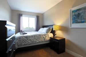 a small bedroom with a bed and a window at Boardwalk Homes Executive Suites in Kitchener
