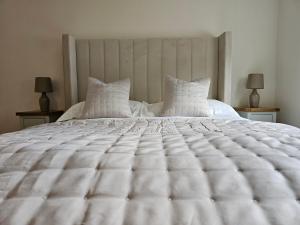 a bedroom with a large white bed with two lamps at Oakmere Apartments in Chinley