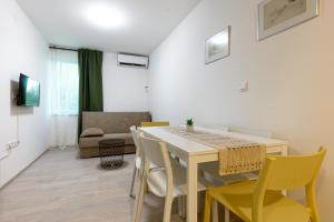 a dining room with a white table and yellow chairs at House Pavel in Osijek