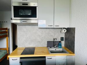 a small kitchen with a sink and a microwave at studio 4 pers praloup 1600 in Uvernet +2 photos