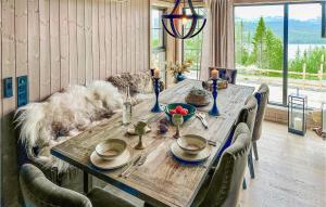 une table en bois avec des chaises et un chien assis autour de celle-ci dans l'établissement Gorgeous Home In Gl With Sauna, à Gålå