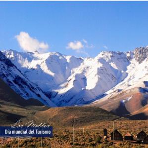a snow covered mountain range with houses in the foreground at Pueblo Andino Los Molles in Malargüe +1 photo