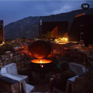 Pueblo Andino Los Molles في مالارغي: شخص يجلس بجوار جدار من الطوب مع النار