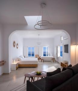 a white living room with a bed and a couch at Elia Family Suites in Fira