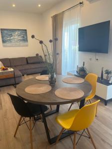 a living room with a table and yellow chairs at Apartman Sea story Mali Lošinj in Mali Lošinj