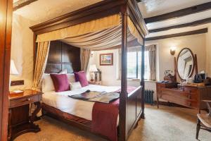 The Jamaica Inn, Bodmin, Cornwall في Bolventor: غرفة نوم مع سرير مظلة مع مكتب ومرآة