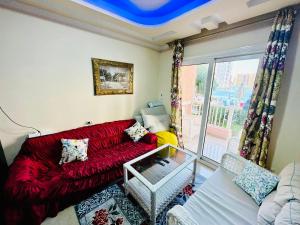 a living room with a red couch and a window at Sia Lagoon 2 BR Porto Golf Marina Apartment with Garden Families only in El Alamein