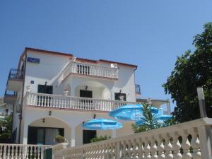 a white building with blue umbrellas in front of it at Gästehaus Sofija Unterkunft mit Frühstück, Privatparkplatz und Klimaanlage in Grebaštica