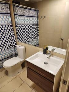 a bathroom with a sink and a toilet and a mirror at Cómodo departamento diario. in Iquique