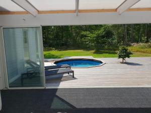 a patio with a swimming pool and a deck at The Black and White cabin with Spa bath in Västra Torup