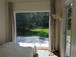 um quarto com uma cama e uma grande porta de vidro deslizante em The Black and White cabin with Spa bath em Västra Torup