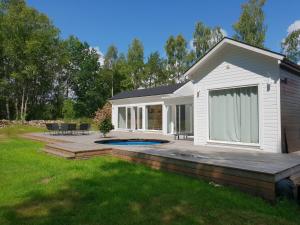 a house with a deck and a swimming pool at The Black and White cabin with Spa bath in Västra Torup