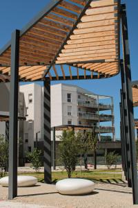 einen Pavillon in einem Park mit einem Gebäude im Hintergrund in der Unterkunft Appartement nouveaux quartier Bologne à deux pas de Mosson, WiFi, climatisation et parking gratuit in Montpellier