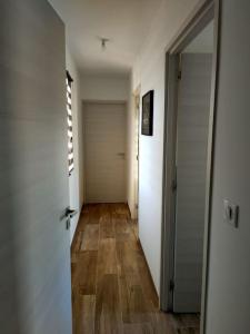 un pasillo vacío con puerta y suelo de madera en Appartement neuf avec balcon et 2 chambres, en Saint-Florent