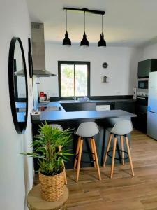 a kitchen with a black counter and stools in it at Appartement neuf avec balcon et 2 chambres in Saint-Florent