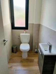 a bathroom with a white toilet and a sink at Appartement neuf avec balcon et 2 chambres in Saint-Florent