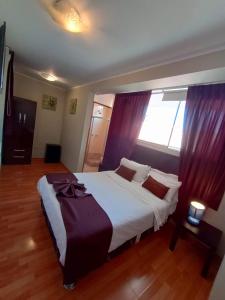 a bedroom with a large white bed with purple curtains at CasaHotel El Tambo Huancayo in Huancayo