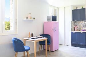 a kitchen with a pink refrigerator and a table and chairs at LE GLAMOUR *STUDIO *PARKING PRIVE* *WIFI*CALME* in Lourdes