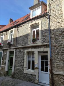ein altes Steingebäude mit einer weißen Tür und Fenstern in der Unterkunft Maison cosy au cœur de la vieille ville in Boulogne-sur-Mer