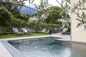 einen Pool im Hinterhof mit Stühlen und Bäumen in der Unterkunft Hotel Stefanshof in Plaus