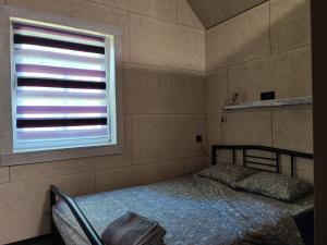 ein kleines Schlafzimmer mit einem Bett und einem Fenster in der Unterkunft BIRZI Parkside Lodge 